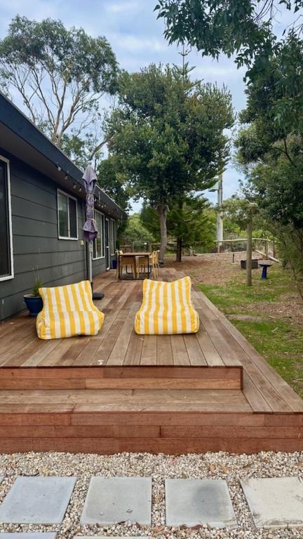 a wooden deck with two yellow and white pillows at The Deck @ VB - Linen, Wi-Fi, Pets, Secured Yard in Venus Bay