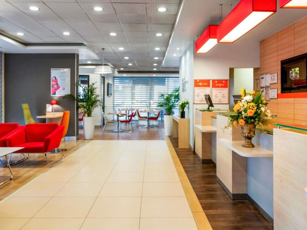 an office lobby with red chairs and tables at Ibis Izmir Alsancak in İzmir