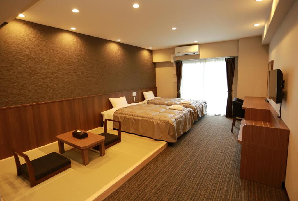 um quarto de hotel com uma cama e uma televisão em The Base Sakai Higashi Apartment Hotel em Sakai