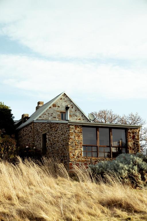 a stone house sitting on top of a field of grass at Shepherd's Cottage at Lisdillon Estate in Little Swanport