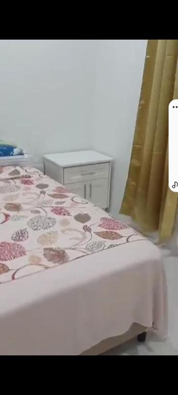 a bedroom with a bed with a pink floral bedspread at Sunset Apartment in Grand Anse