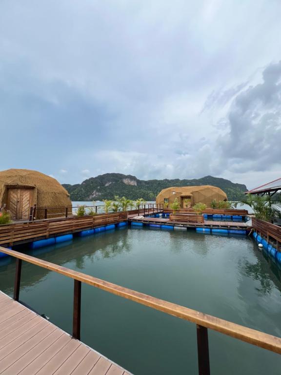 a pool of water with thatched roofs on a resort at Coconest THREE Langkawi in Tanjung Rhu
