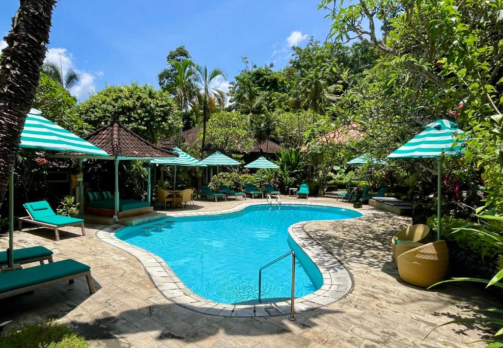 a swimming pool with chairs and umbrellas at a resort at DW Jungle Resort - Candidasa in Candidasa