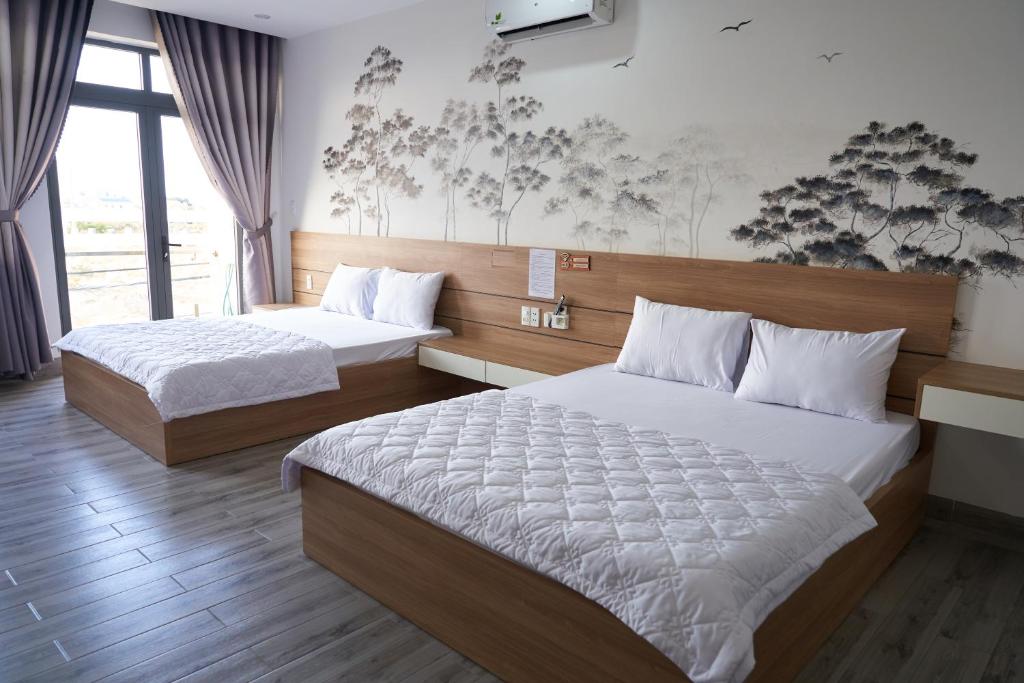 a bedroom with two beds and a large window at Hotel Tâm Đan in Ðông Tác (1)