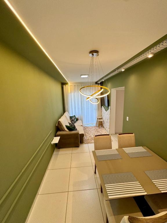 a living room with a table and a couch at Apartamento 2 Quartos Aconchegante - Ar Condicionado nos Quartos - 1 Cama Casal - 2 Camas de Solteiro com Auxiliar - Cozinha Completa - Estacionamento Gratuito in Três Lagoas