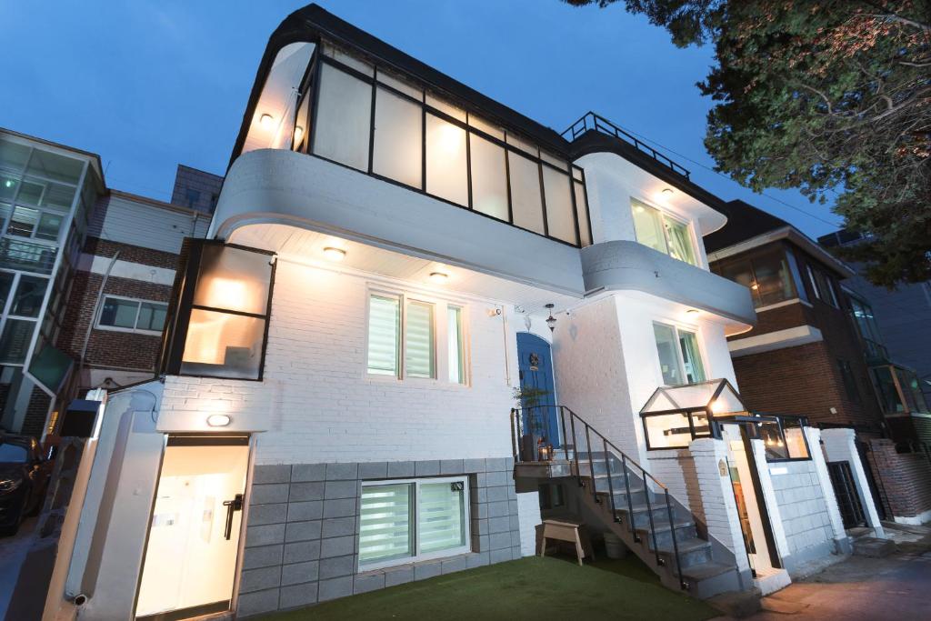 une grande maison blanche avec un escalier en face de celle-ci dans l'établissement Neat House, à Séoul