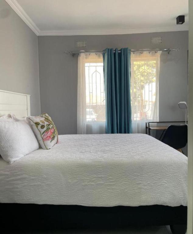 a bedroom with a large bed and two windows at Upendorest in Gaborone