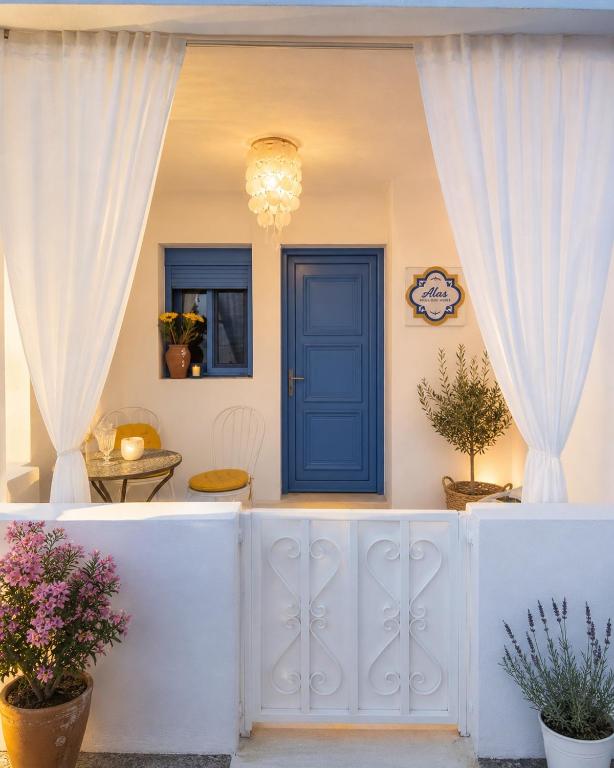 a white fence with a blue door and curtains at Álas Holiday Home in Archangelos