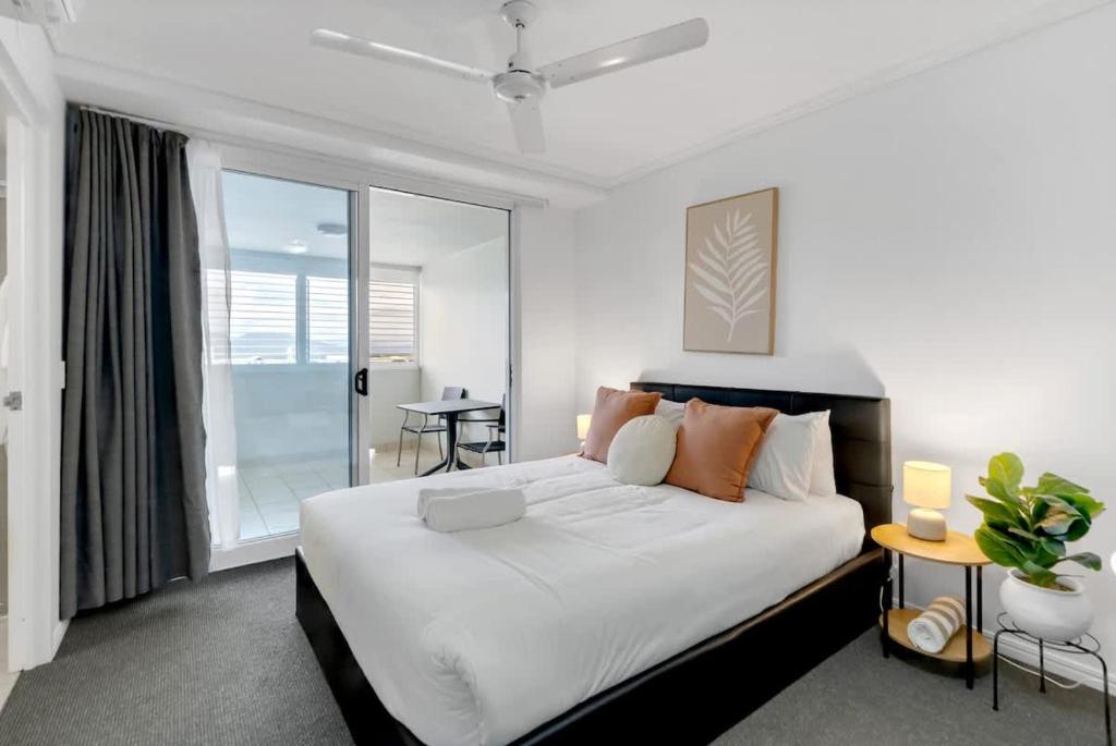 a bedroom with a large white bed with orange pillows at McLeod Nook - Poolside Studio by Waterfront & Market in Cairns