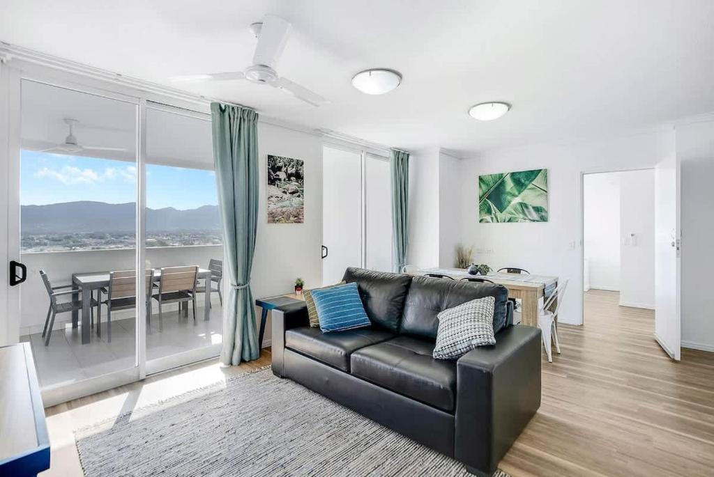 a living room with a couch and a dining room at Cairns City Escape - Elevated Modern Haven with Pool in Cairns