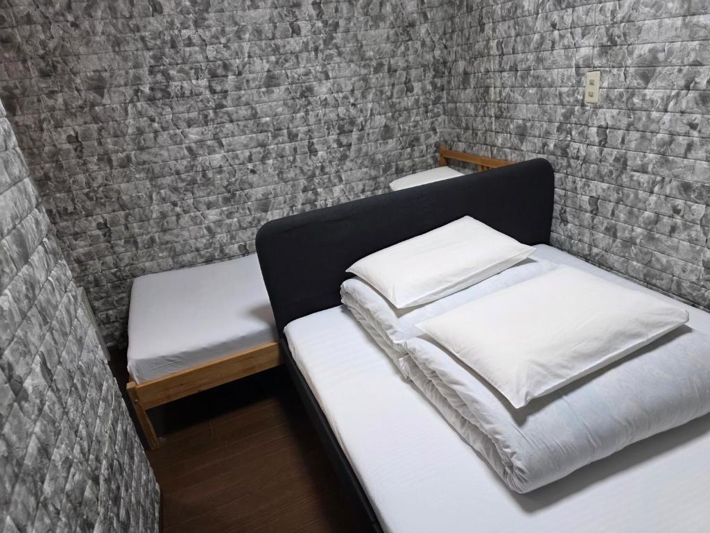 two beds in a room with a brick wall at Sophiearth Apartment in Tokyo