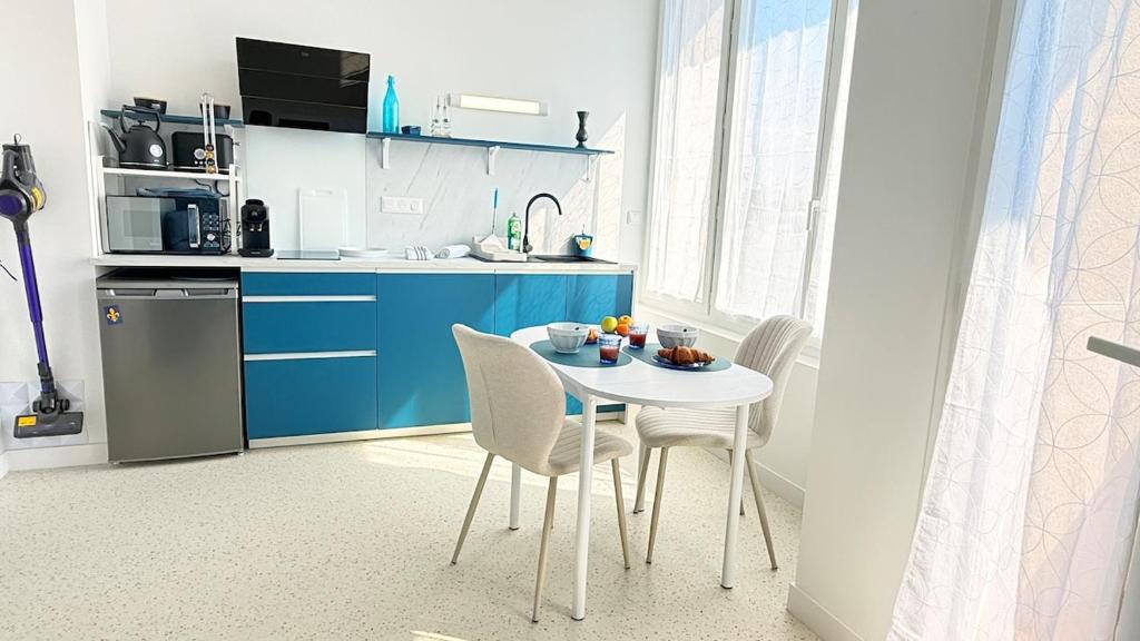 a kitchen with a table and chairs in a kitchen at Studio Ty Lys lumineux, climatisé, balcon, parking gratuit Classé 3 étoiles in Blois