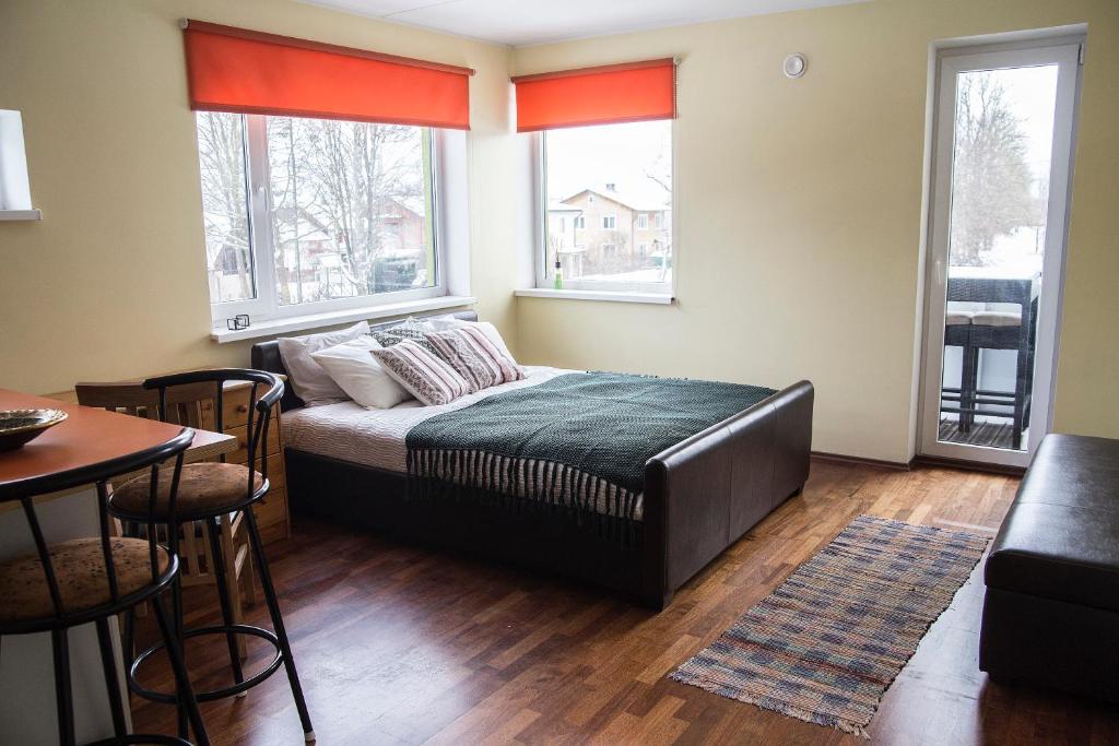 a bedroom with a bed and a table and two windows at Modern Apartment in Tartu