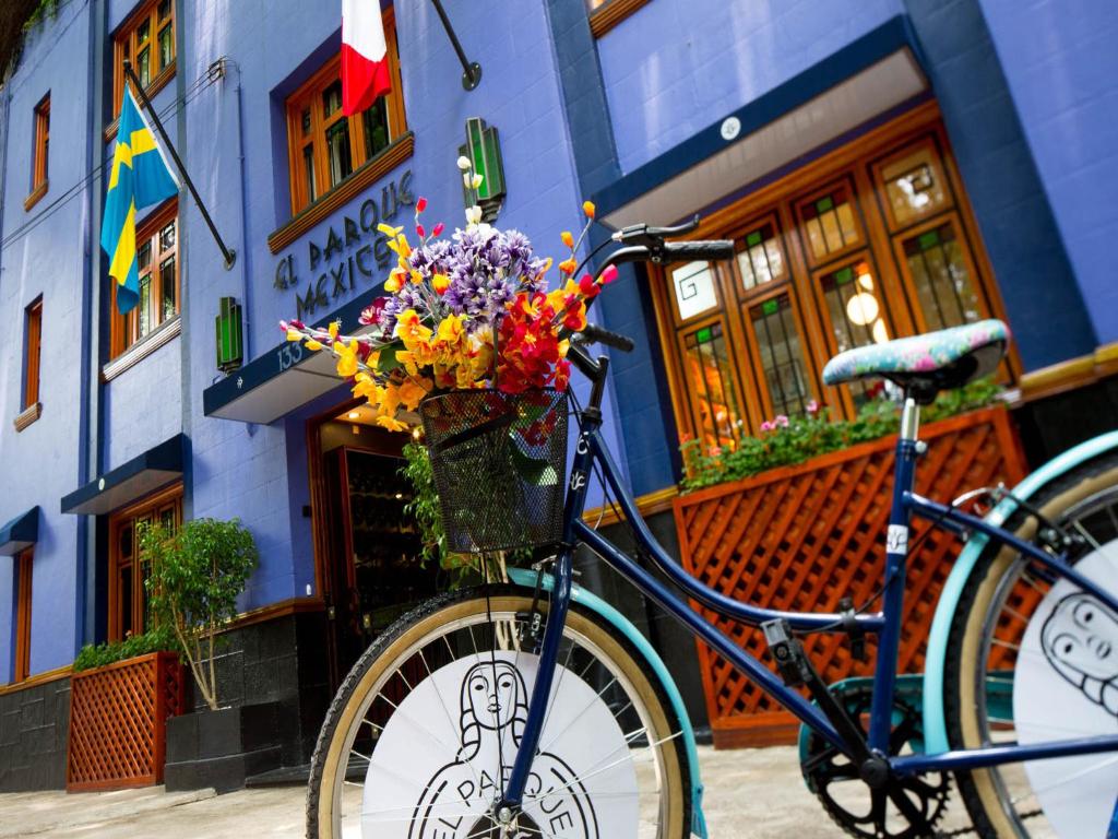 un vélo garé devant un bâtiment avec une corbeille de fleurs dans l'établissement Hotel Parque México Boutique, à Mexico