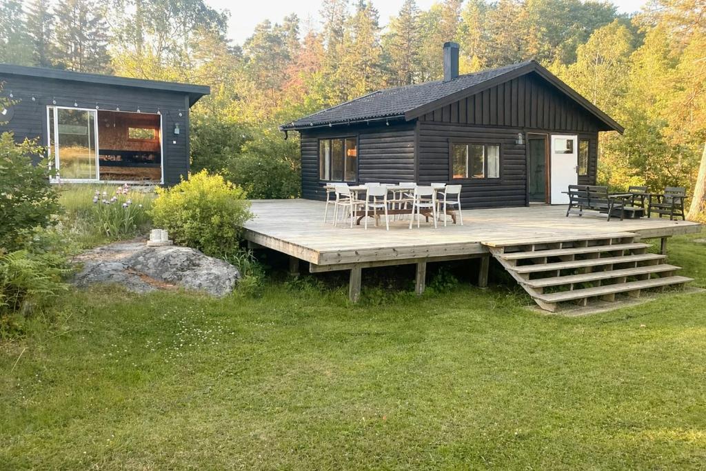 a log cabin with a table and chairs on a deck at Nature And Veranda In Perfect Alignment in Djurhamn