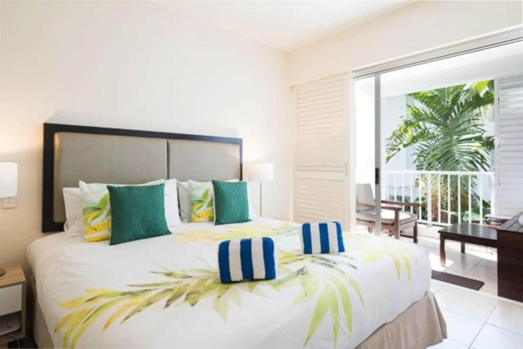 a bedroom with a large bed with green and yellow pillows at Couple's Coastal Haven Retreat at The Beach Club in Palm Cove