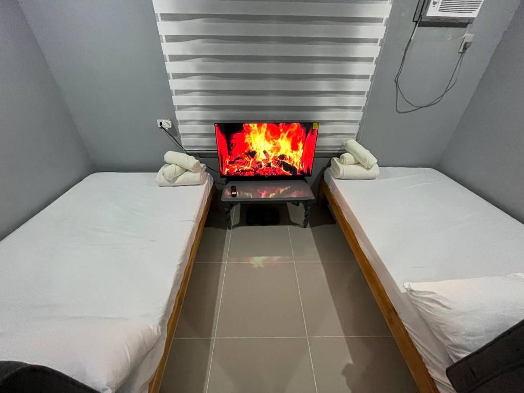 zwei Betten in einem Zimmer mit einem Kamin dazwischen in der Unterkunft A Residences in Daet