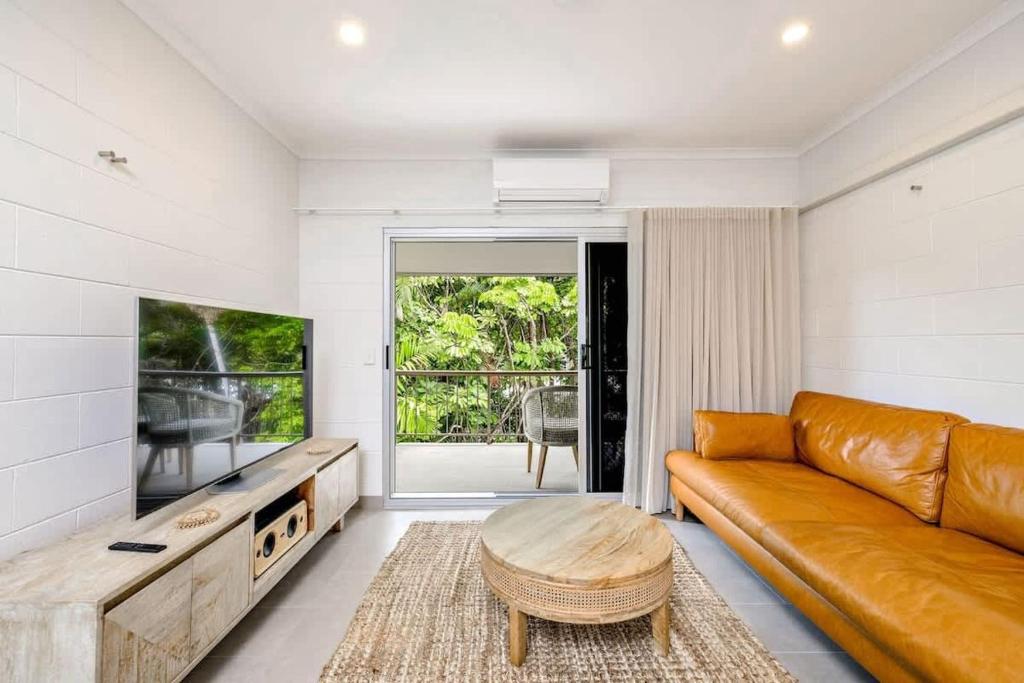 a living room with a leather couch and a table at The Tropical Trinity - A Breezy Beachside Getaway in Trinity Beach