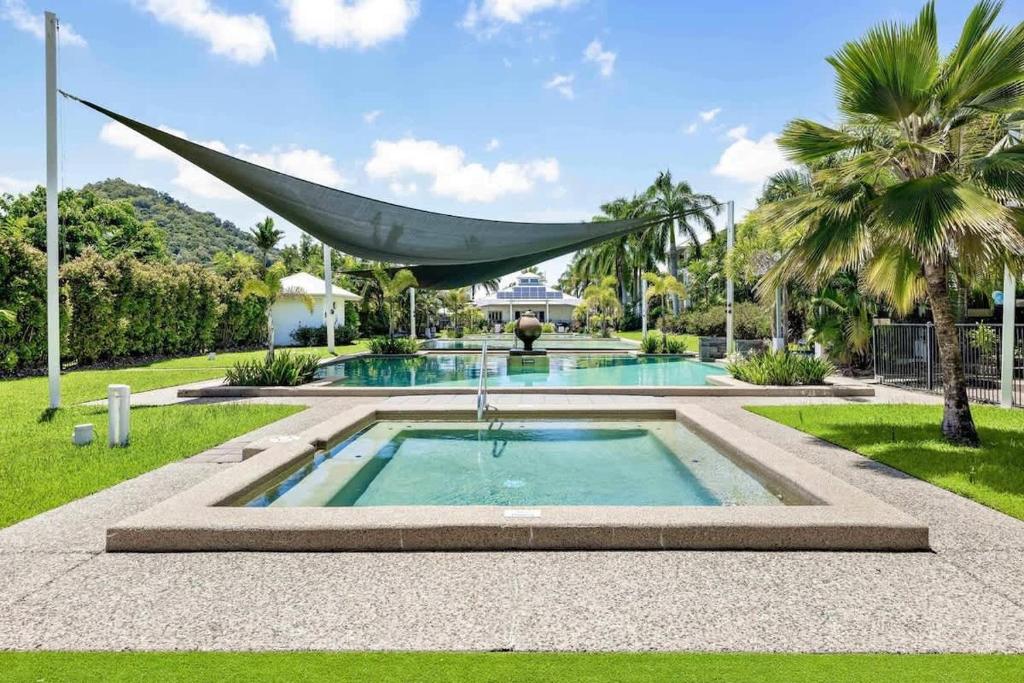 a swimming pool with a hammock hanging over it at Trinity Beach Bliss - Experience Tropical Living in Trinity Beach