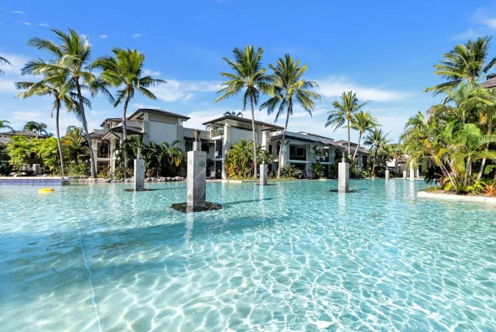 a large swimming pool with palm trees and houses at 'Saltwater Studio' Experience Resort-style Bliss in Craiglie