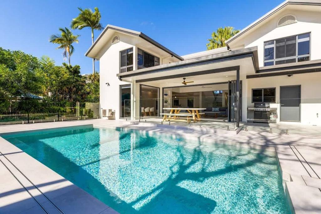 a swimming pool in front of a house at Raphari At The Cove - A Stunning Poolside Escape in Palm Cove