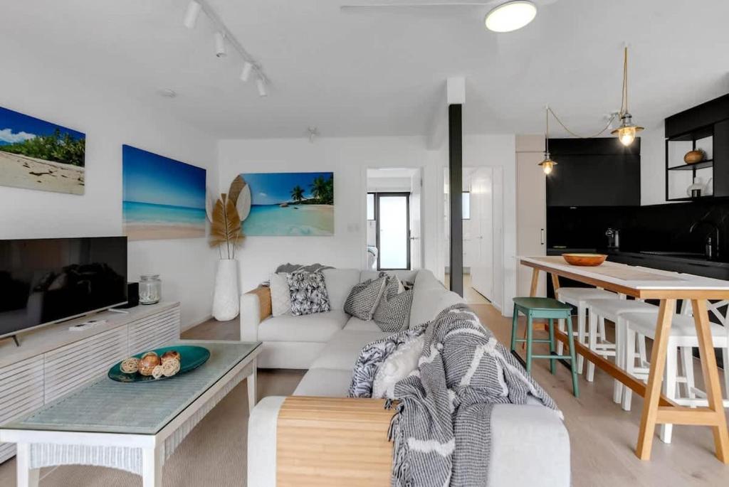 a living room with a white couch and a table at Mira - Poolside Beach Retreat by Four Mile Beach in Port Douglas
