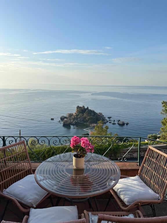 a table with a vase of flowers on a balcony at La Bergerie Isolabella sea view B & B in Taormina