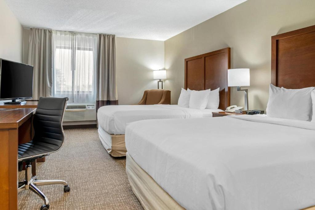 a hotel room with two beds and a desk and a computer at Comfort Inn Manistique in Manistique