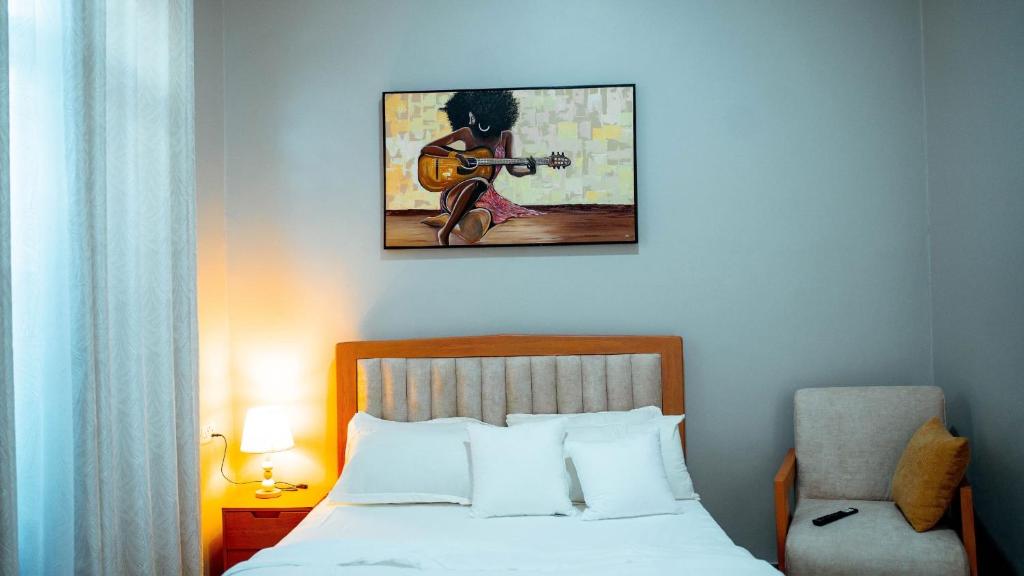 a bedroom with a bed and a painting of a woman playing a guitar at Ligas homes in Dodoma
