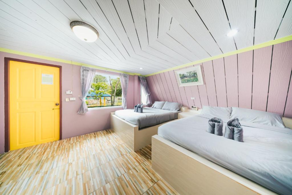 a bedroom with two beds and a yellow door at แฝดสามการ์เด้นท์รีสอร์ท แสมสาร Fadsarm Garden Resort Samaesan in Sattahip
