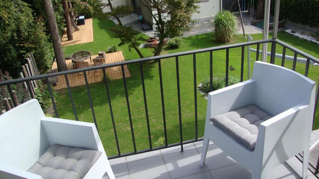 two white chairs on a balcony with a lawn at B&B Laupenring, Basel in Basel