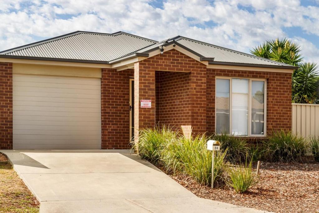a red brick house with a garage at Comfort on Mozart in Shepparton