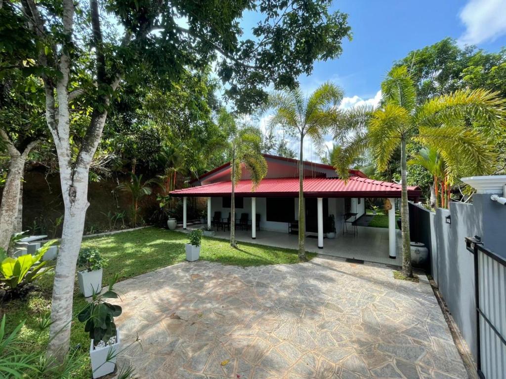 a house with a red roof and palm trees at Villa One Hikkaduwa in Hikkaduwa