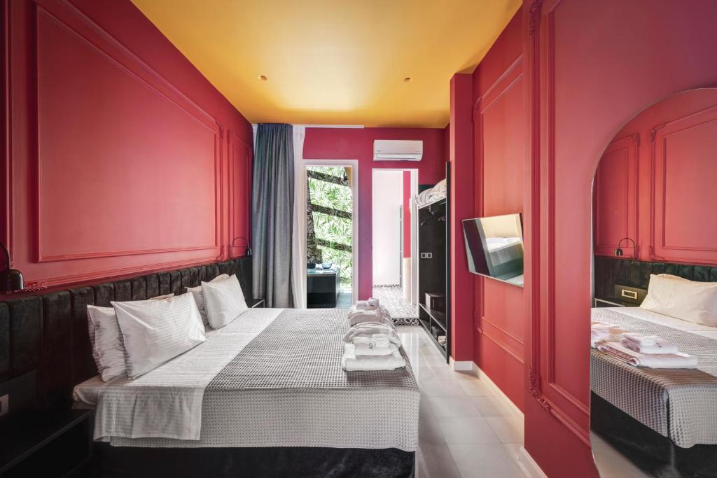 a red room with two beds and a window at ATELIER5 Suites in Ermoupoli