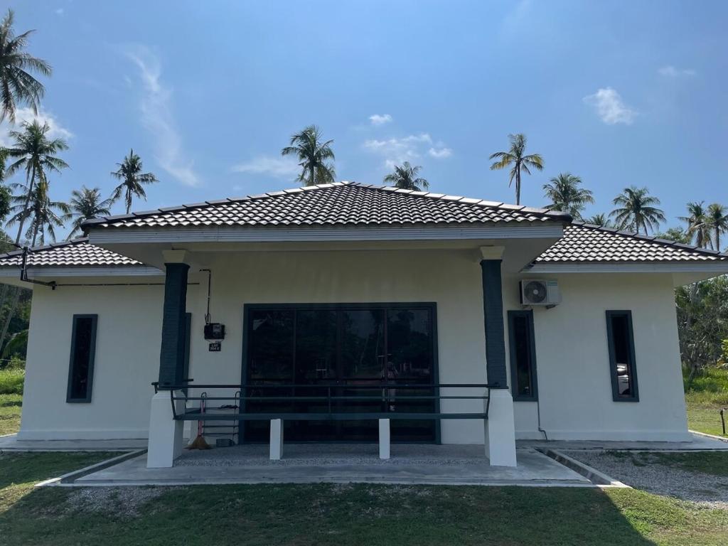 a small white house with palm trees in the background at DBreeze Homestay in Pengerang