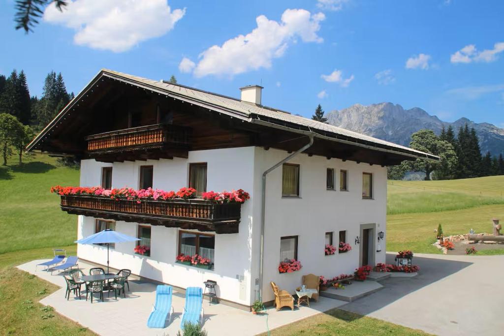 a white house with a balcony and tables and chairs at Oberharreithhof in Sankt Martin am Tennengebirge