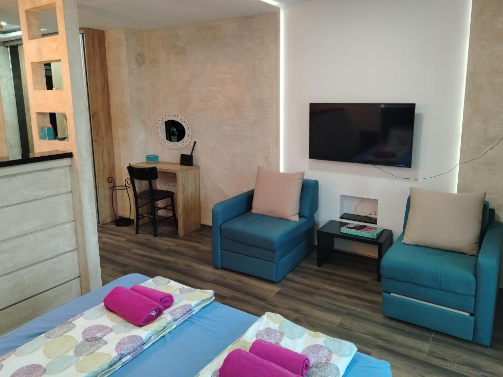 a living room with two blue chairs and a flat screen tv at Apartman Harmony 5 in Banja Koviljača