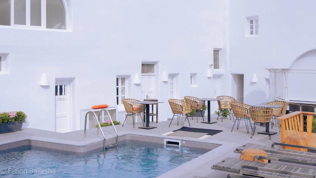 a patio with a table and chairs next to a pool at Nomikos Villas in Fira