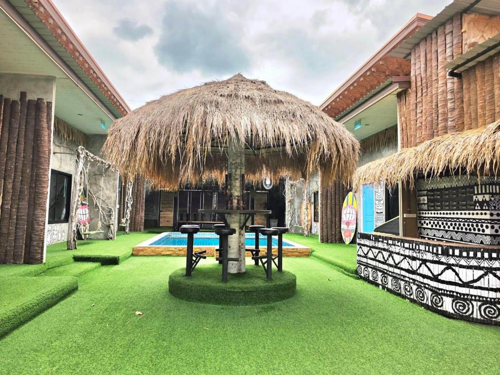 a patio with a table and a straw umbrella at Tiki Pool Pattaya in Ban Nong Pla Lai