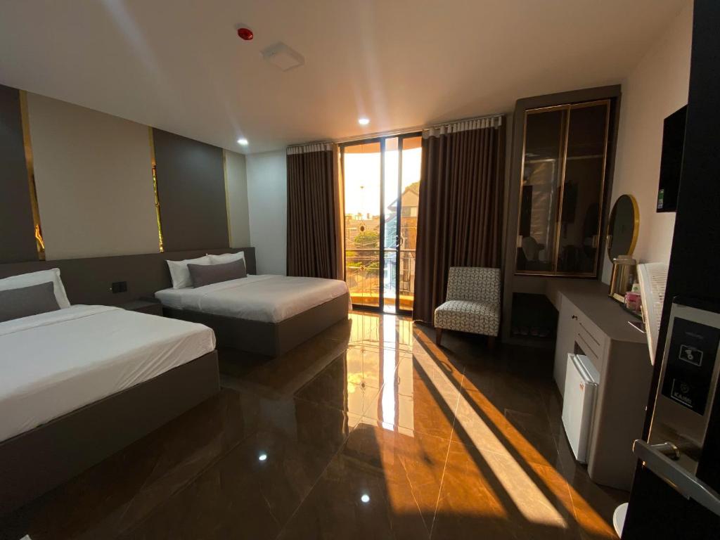 a hotel room with two beds and a balcony at Kim's Hotel in Buon Ma Thuot