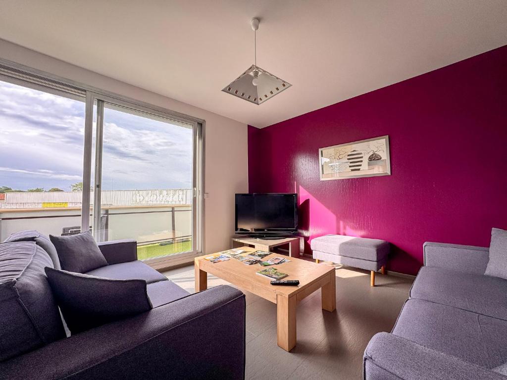 a living room with purple walls and a couch and a table at Appartement Lily-rose in Cerizay