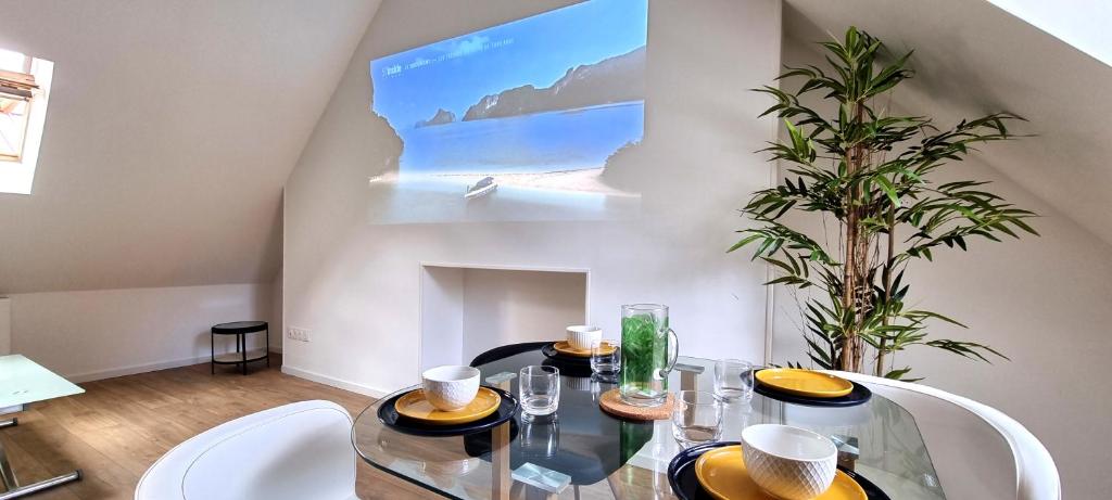 a dining room with a glass table and white chairs at Le Charmant in Dieppe