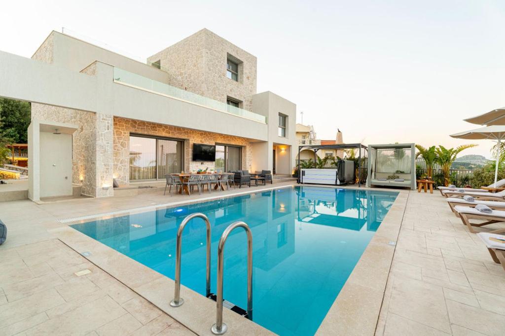 a swimming pool with chairs and a house at Arfna Grand Villa in Afantou