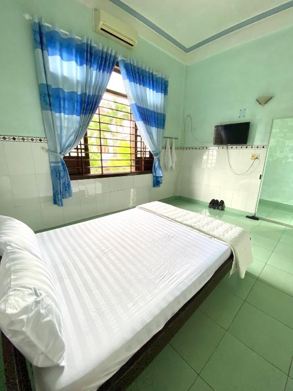 a large white bed in a room with a window at Quốc Khánh Guest House in Thôn Lại Thê
