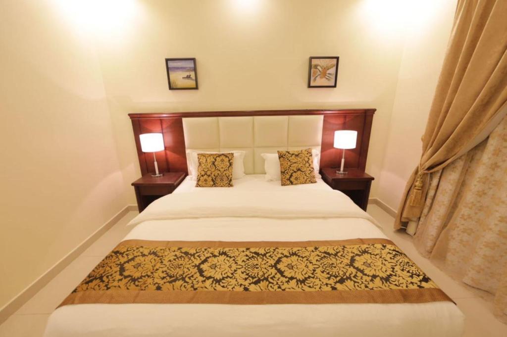 a bedroom with a large bed with two lamps at Lara Al Jawf Hotel Apartments in Arar