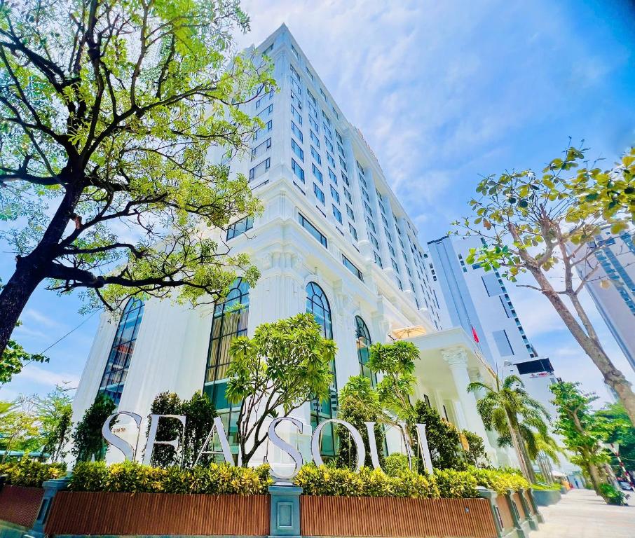 a tall white building with trees in front of it at Sea Soul Hotel in Nha Trang