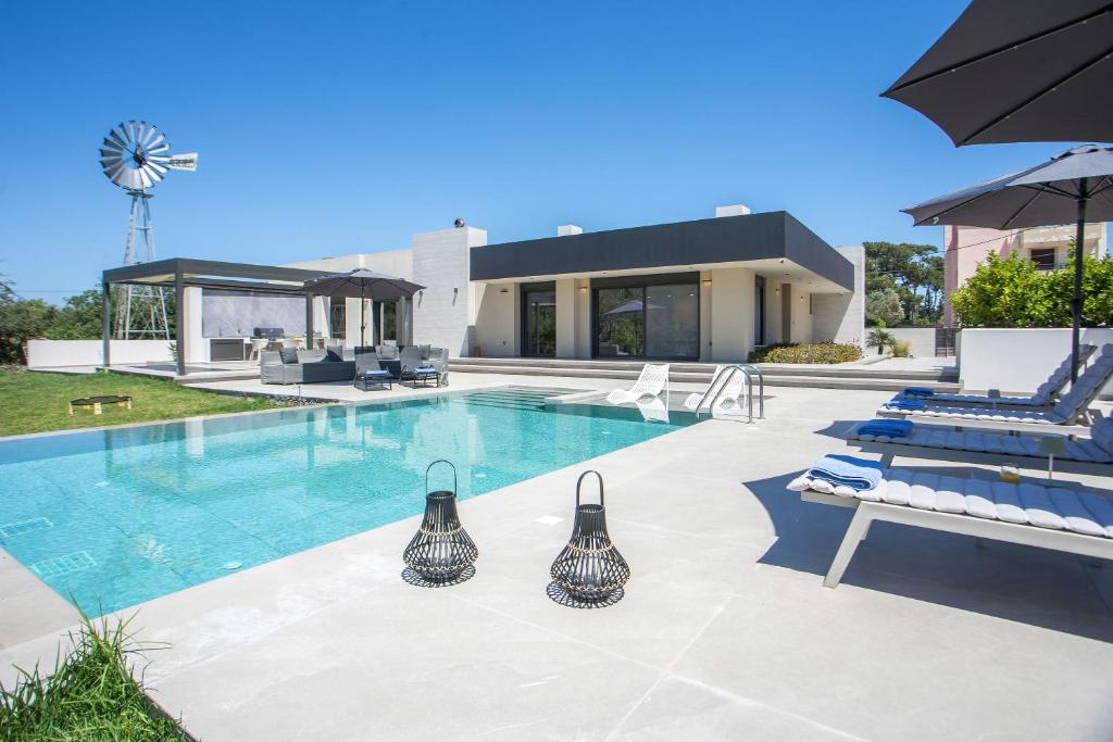 a swimming pool with two blue chairs and a house at Casadi Luxury Villa in Ialysos