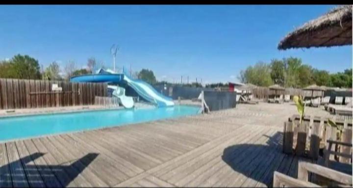 a blue slide in a swimming pool with a playground at Mobil home zen élégant in Mimizan