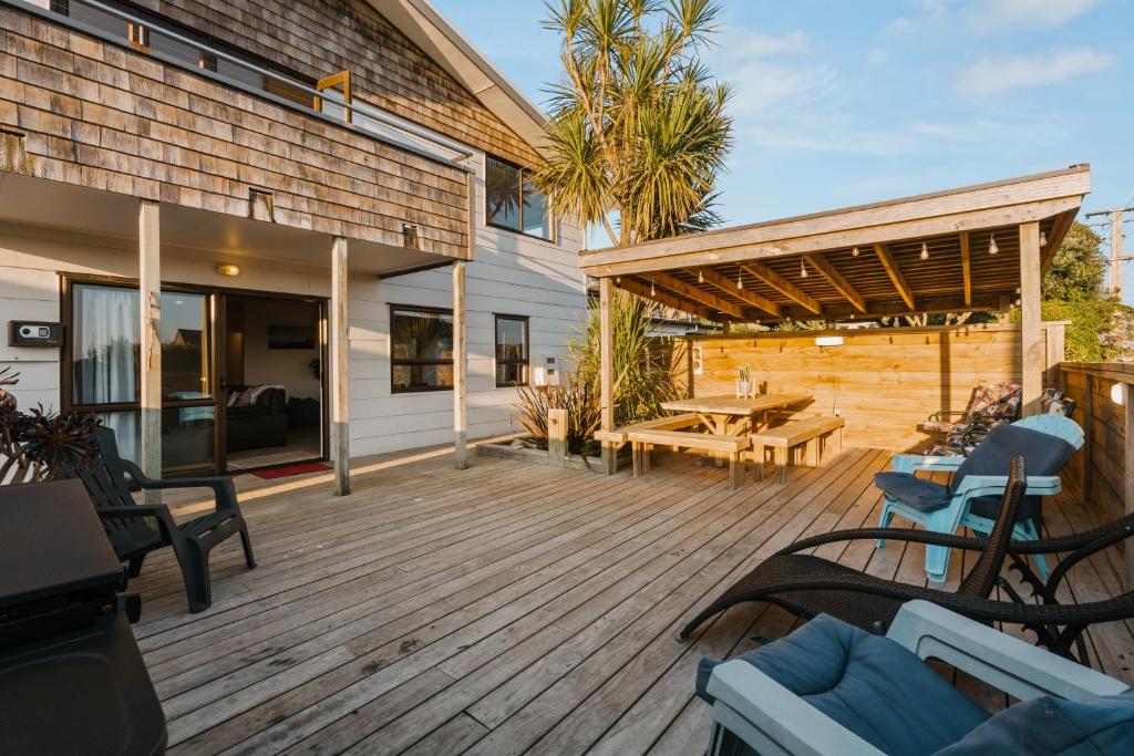 a deck with chairs and a picnic table on a house at Waterfront location with estuary outlook and ocean beach access - sleeps 19 in Pukehina