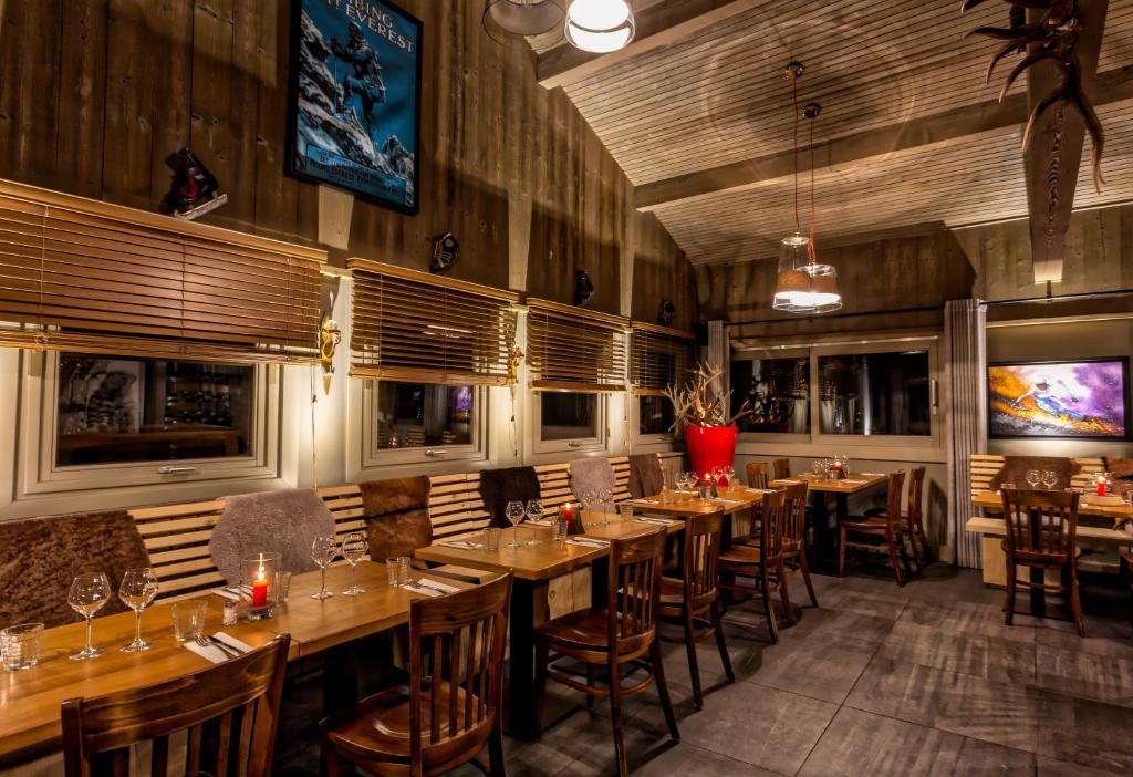a restaurant with wooden tables and chairs in a room at Hillary Hotel in Les Menuires